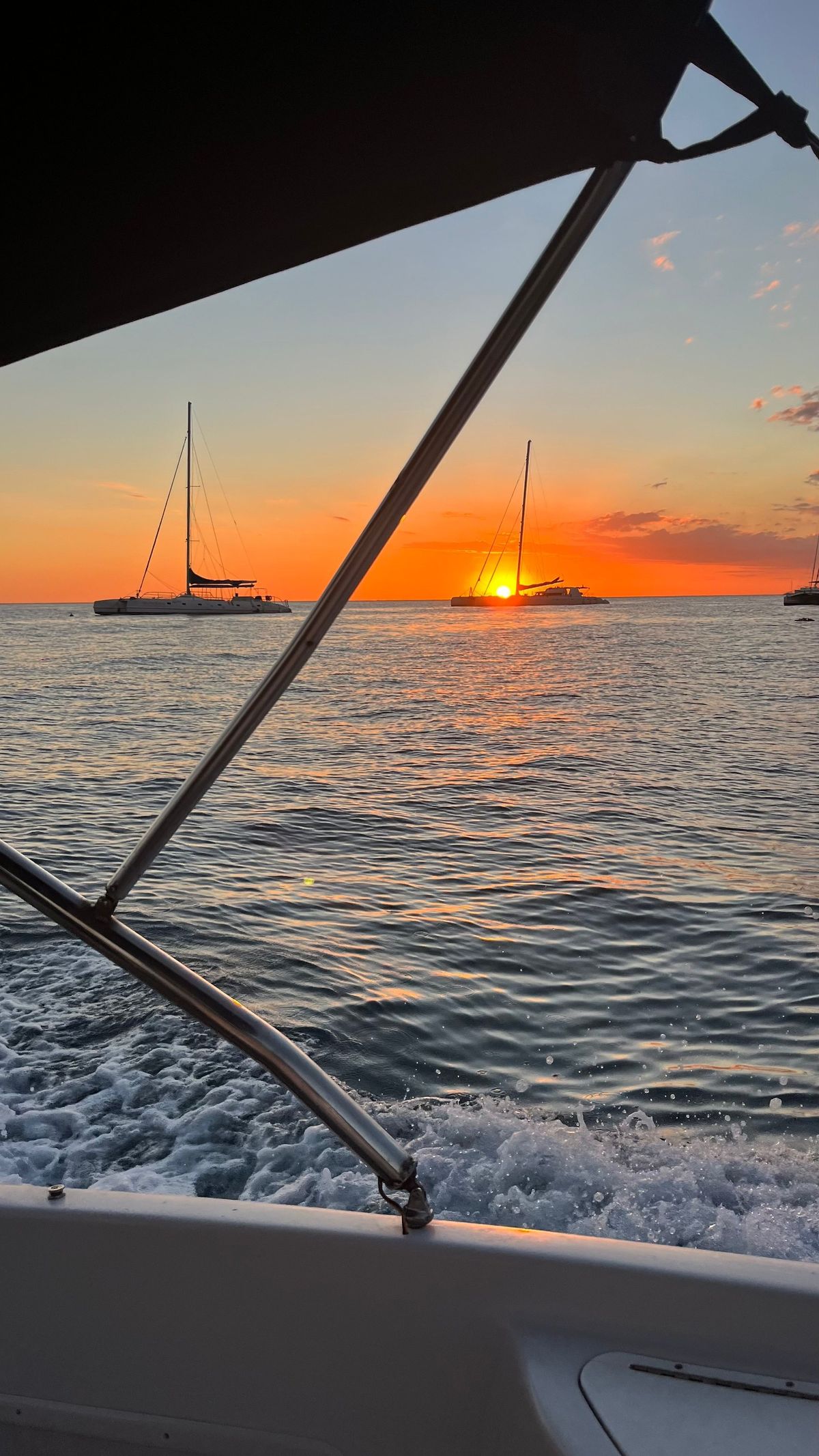 Atardecer naranja sobre el mar con veleros al fondo