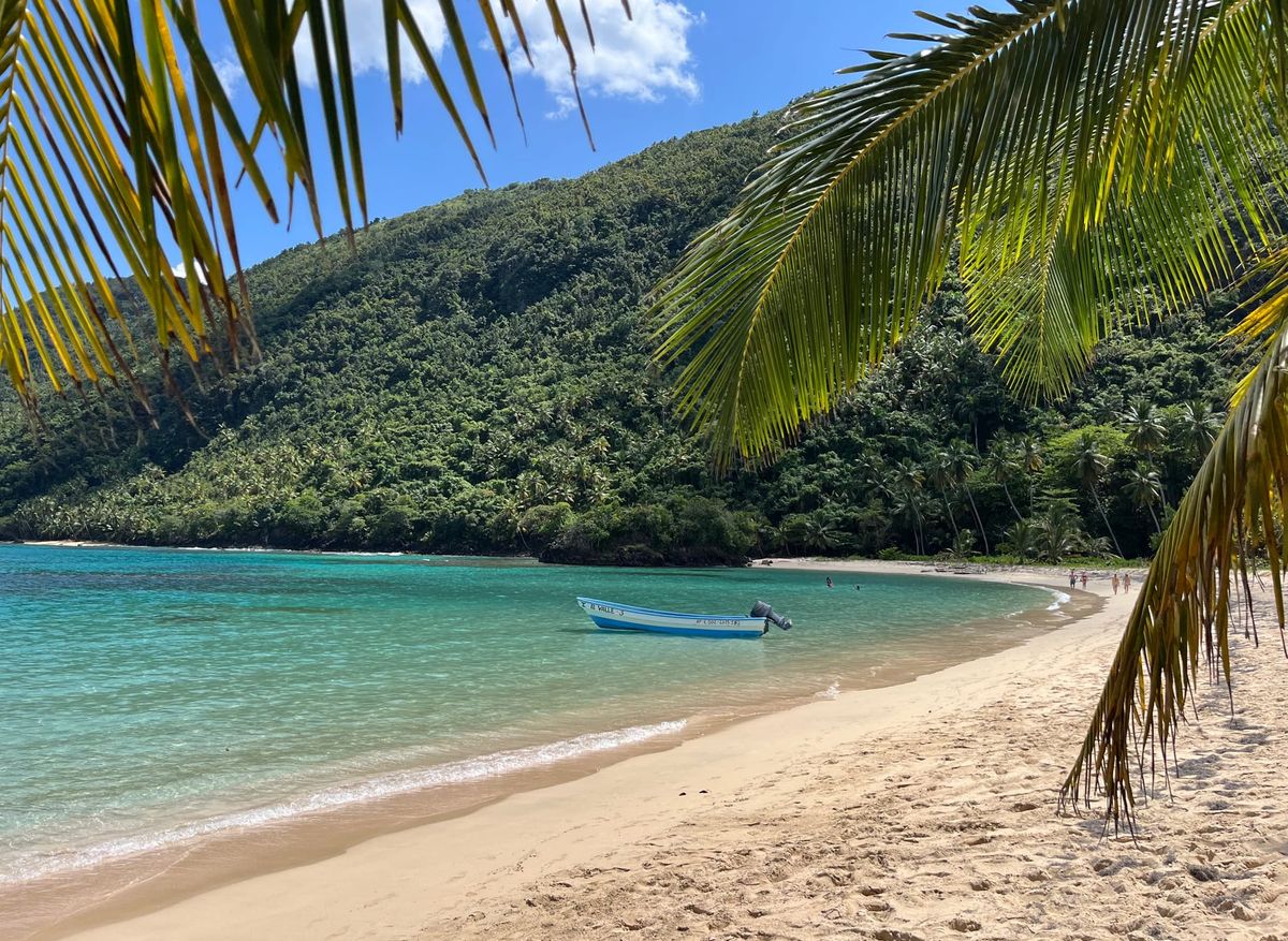 Playa de arena blanca y agua turquesa en una bahía rodeada de montañas